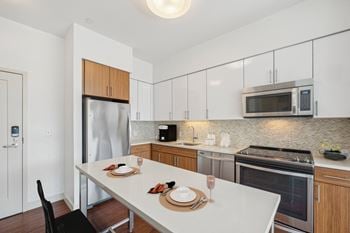 A modern kitchen with a dining table set for two.